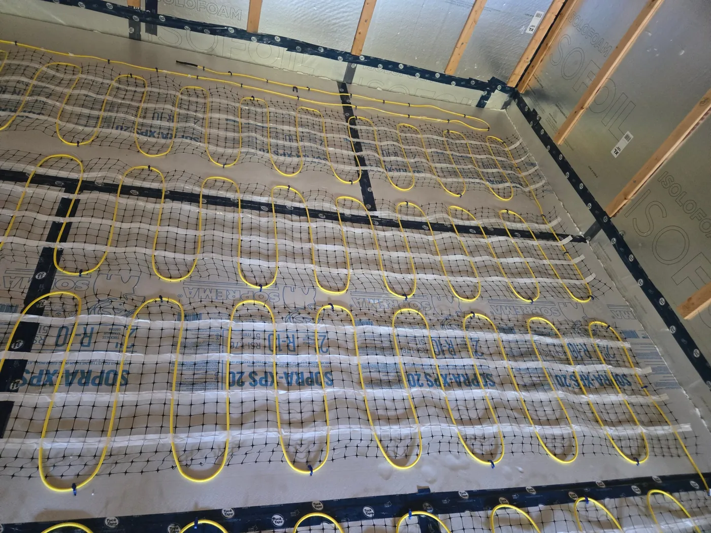 Câbles chauffants jaunes installés sur isolant avant la coulée d'un plancher chauffant en béton
